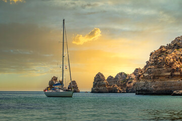 Beautiful beach at sunset with boats, kayaks and stand up boards. Dona Ana beach in the Algarve -...