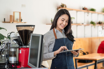 Small owned coffee shop Asian woman stand by using a tablet business and technology in the field of service.