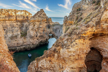 Blue boat on a rocky cavern at Ponta da Piedade, Lagos, one of the most beautiful areas of the...