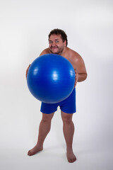 Funny fat man training with a fitness ball. Adult guy on a white background. Copy space. Active sports with a diet.