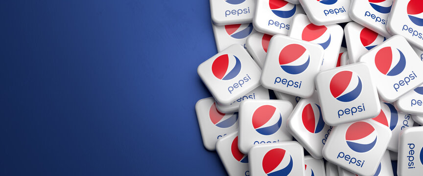 Logos of the cola brand of food, snack and beverage company Pepsi Corporation on a heap on a table. Copy space. Web banner format.