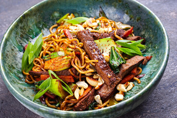 Modern Style Pad Thai-Rindfleisch mit Angus Roastbeef Streifen, Nudeln und Gemüse, serviert als close-up in einer Schale im nordischen Design
