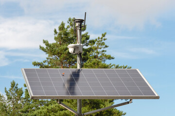 Solar powered surveillance camera. Solar panels powering a surveillance camera in a city park...