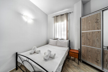 Fototapeta na wymiar Bedroom of non standard shape, in light colors, equipped with double bed, cupboard with sliding doors.