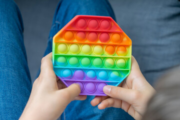Boy playing with sensory pop it fidget toy at home. Push pop-it fidgeting game helps relieve...