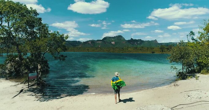 Man with Brazilian flag on a blue lake celebrating freedom.