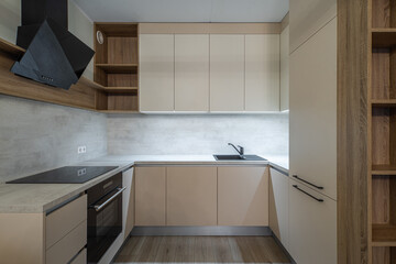 Modern interior of new beige kitchen with oven. Wooden shelves.