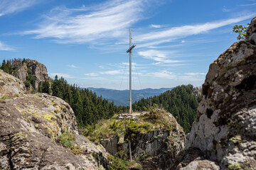 View on coniferous woods and Rocky mountains in Bulgaria with cross on top of it.