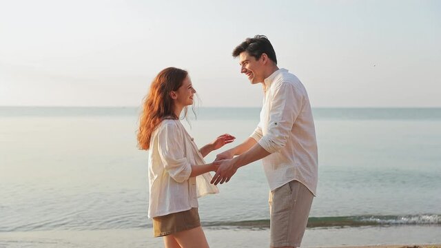 Smiling happy charming fun romantic young couple two friends family man woman 20s in white clothes hugging dancing together at sunrise over sea beach ocean outdoor seaside in summer day sunset evening