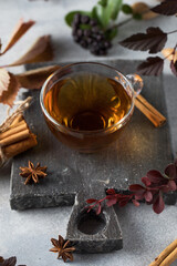 Delicious freshly brewed aromatic tea in a glass cup with a board and various natural ingredients. Tea time