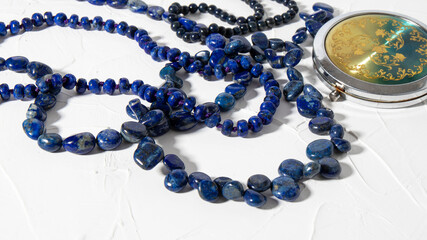 Isolated beautiful different beads made of natural blue lazurite stone on a white background. Retro composition of different lapis lazuli necklaces. 