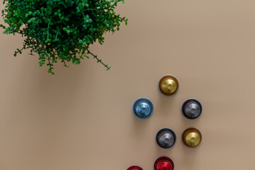 Coffeebreak with a cup of coffee, coffeebeans and green plant on beige background