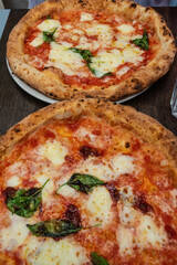 Two freshly baked napolitano pizzas on a table.