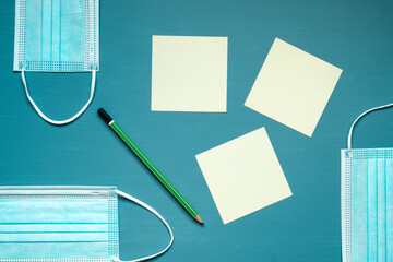 medical face masks, blue color, office, green pencil, reminders, yellow cards, on a blue and turquoise background, photo taken from above