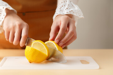woman hands cutting lemon on white cutting board preparing for food and drink