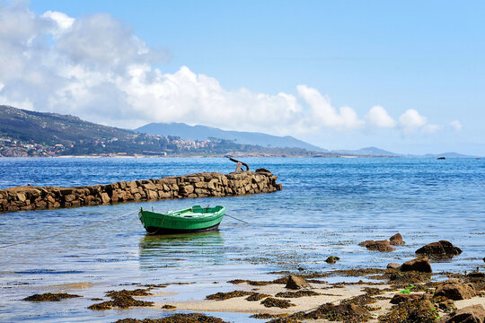 Low tide with a traditional fishing rowboat in the Galician coast, Northern Spain.