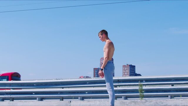 Guy with naked torso doing backflip four times on embankment. Male gymnast, acrobat practising salto backward on city river esplanade. Sportsman training outdoor. Young man does sport outdoor