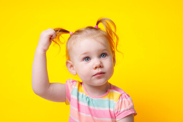 cute caucasian baby girl with ponytails over yellow background