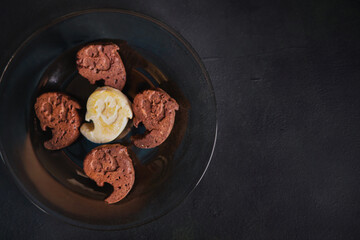 Homemade cakes in the shape of Halloween ghosts. The cookies are on a dark plate. Black background. Copy space.