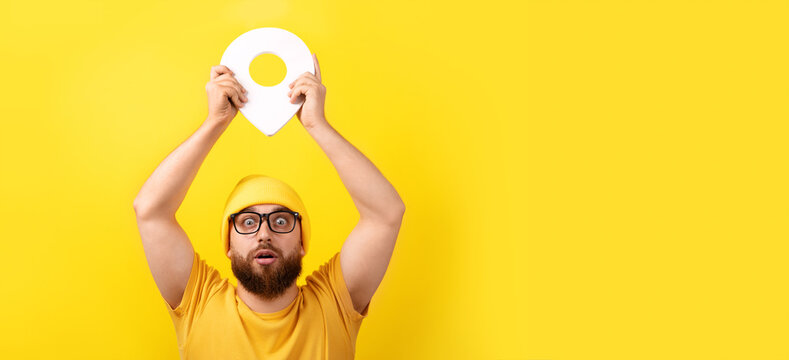 man holding location marker over yellow background, concept navigation and exploration, panoramic image