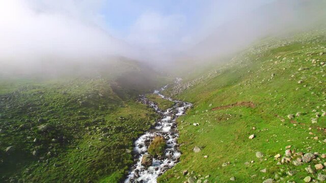 misty mountain river in green meadow, freshwater stream on a foggy morning in sunny mountain valley, aerial view of wild natural environment, Turkey Kackar natural reserve 