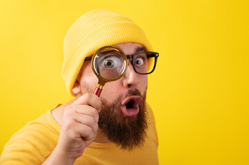 shocked man with magnifier over yellow background