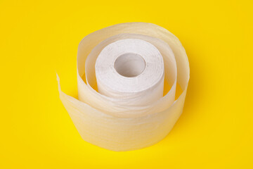 roll of white toilet paper over yellow background