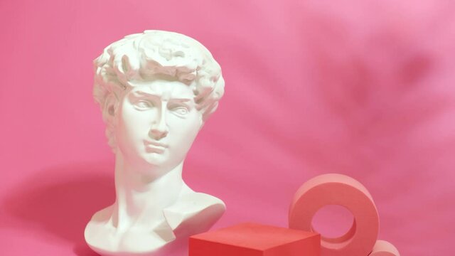 bust of a statue of david and a scene for your product on a pink background, mock up stands for rendering the product, a shadow from a palm leaf Empty showcase for displaying products and goods.
