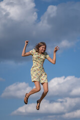 A beautiful girl plays in the field on bales of straw.