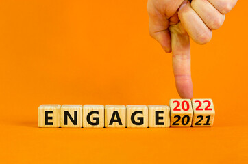 2022 engage and new year symbol. Businessman turns wooden cubes and changes words 'engage 2021' to 'engage 2022'. Beautiful orange background, copy space. Business, 2022 engage and new year concept.