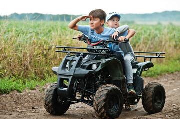 Fototapeta na wymiar Two brothers driving four-wheller ATV quad bike. Happy children moments.