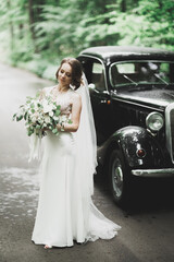 Happy bride in the retro car posing on her weeding day