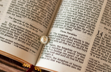 Closeup of open Christian Holy Bible with a pearl of great value. The parables of a hidden treasure...