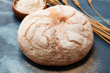 Round soft fresh bread on a blue background. Flour and wheat. Fragrant pastries.