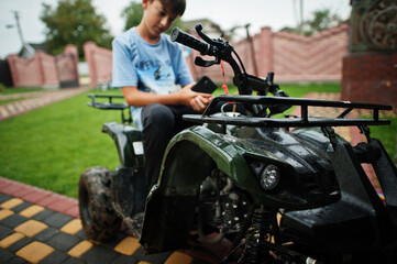 Fototapeta na wymiar Boy in four-wheller ATV quad bike with mobile phone.