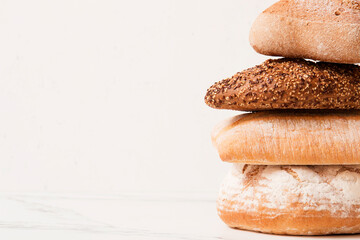 Bread, pastries on a light background. Bread with sesame seeds and seeds, bread texture. Delicious flavored bun. Lots of airy fresh bread.