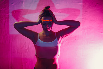 Young adult woman holds hands on head ad having suffering facial expressions with word Headache on...