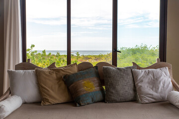 sofa with pillows in front of a window with oceanview