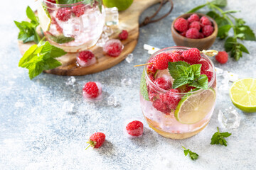 Hard seltzer cocktail with raspberries and lime on a gray stone table top. Copy space.