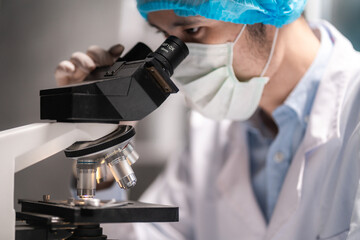 scientist looking through scientific microscope lense in laboratory, scientist doing research in...