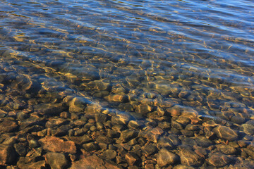 the glare of the sun in the waves running along the rocky shallow water to the shore = = = 