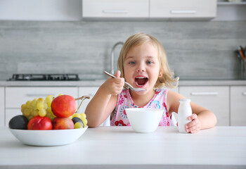 Child girl eating healthy food.Smiling little girl have a meal at kitchen.Kid have fruits and yogurt for lunch. Nutrition concept.