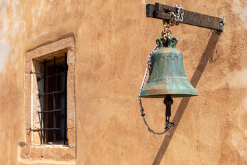 Obraz premium A historical bell in front of a Mediterranean wall