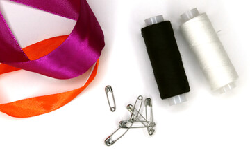Sewing threads, pins and pieces of fabric on a white background