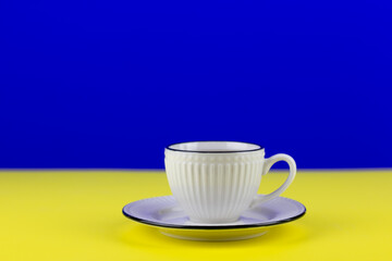 White cup of tea on yellow and blue background