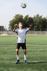 The boy loves to play football, trains with the ball on the artificial turf and scores a goal. The boy plays football