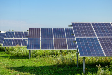 Solar panels installation front view above green grass under clear blue sky on a bright sunny day
