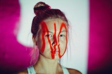 Young adult woman with word NO on her face.