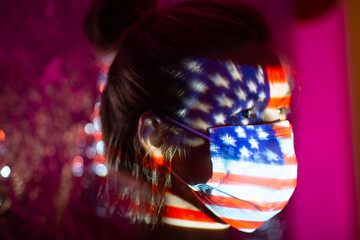 Young woman with USA flag on her face in medical mask.