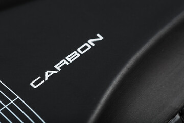Carbon element of cycling shoes with the inscription CARBON on a black background close-up.